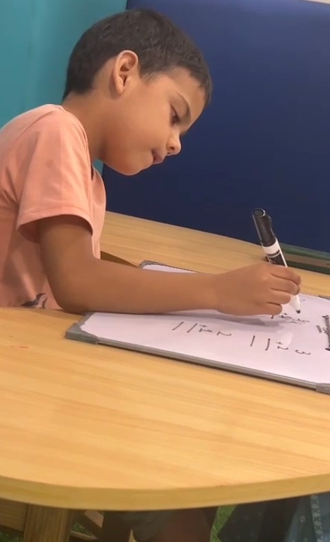 Child practicing early learning and writing skills at a classroom table